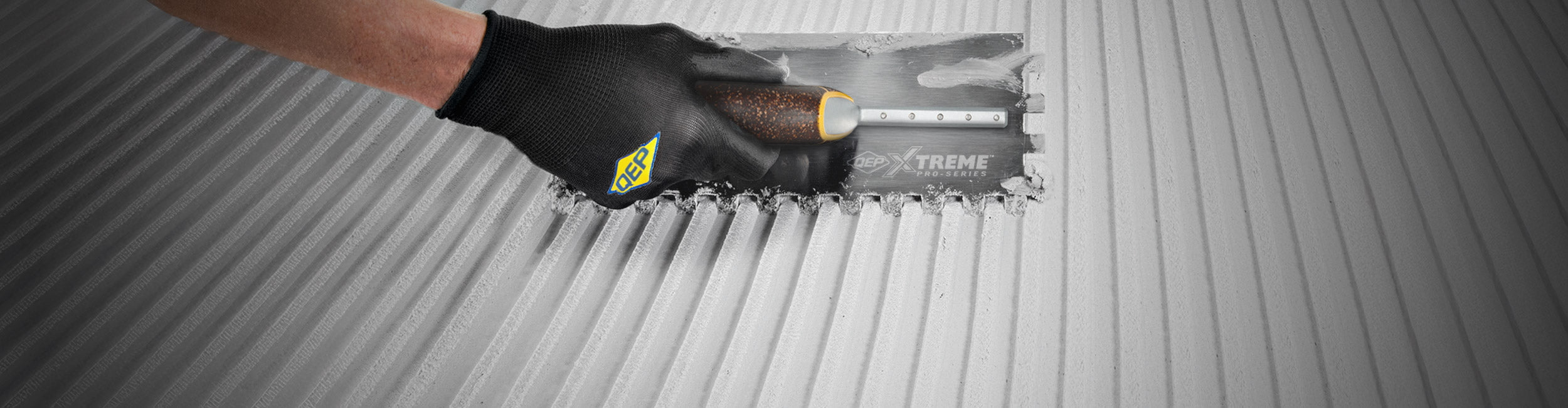 Close-up of hand using QEP's Xtreme Cork Handle Trowel to spread thinset evenly for installation