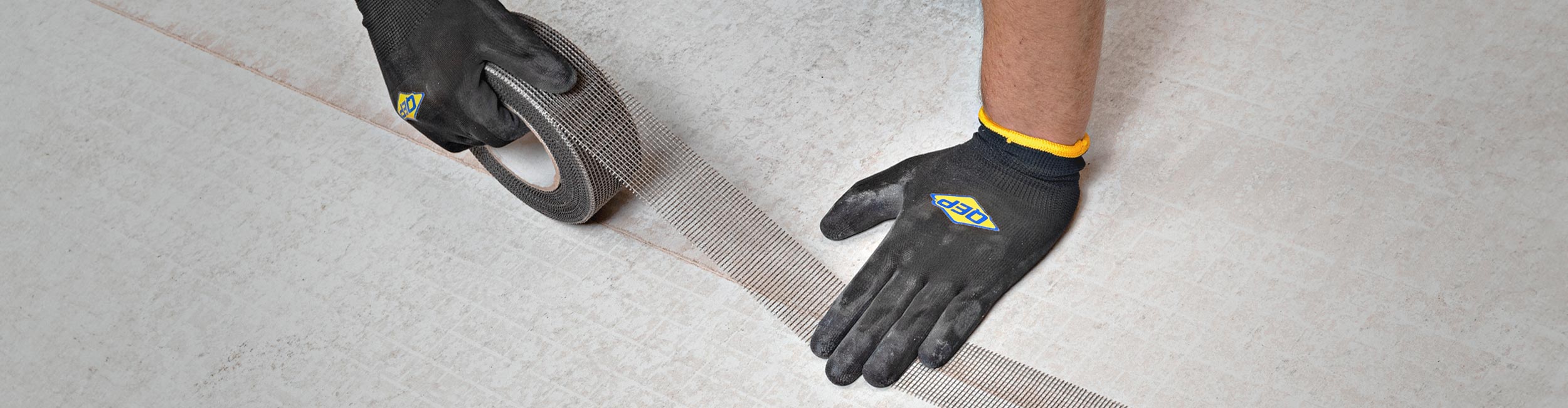 Installer using QEP'S Cement Board Tape to mend the seams of cement backer board together