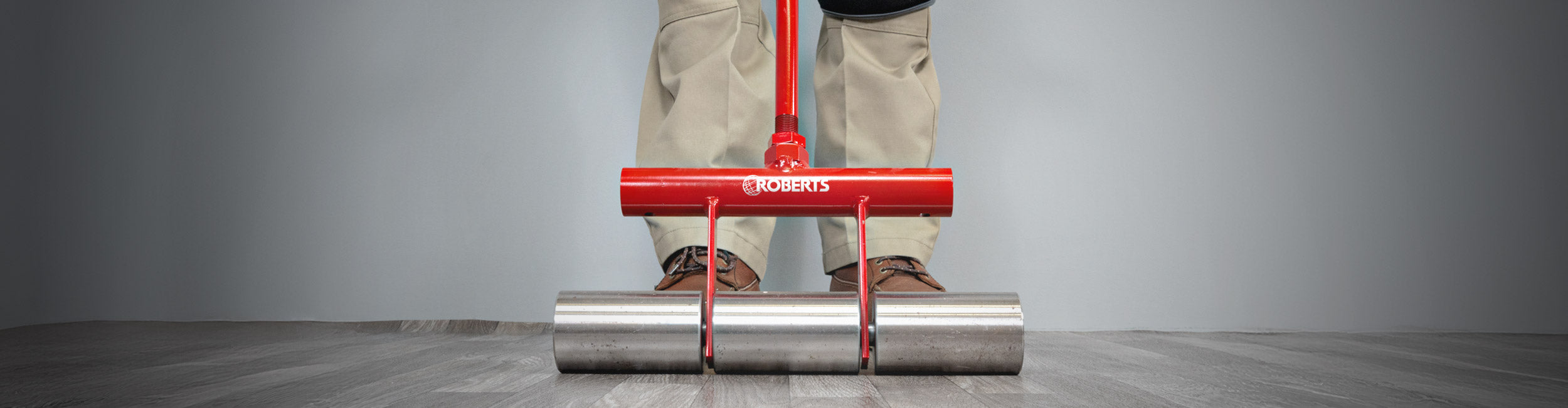 Close-up of installer using ROBERTS 35 lb. Heavy-Duty Flooring Roller to press out sheet vinyl