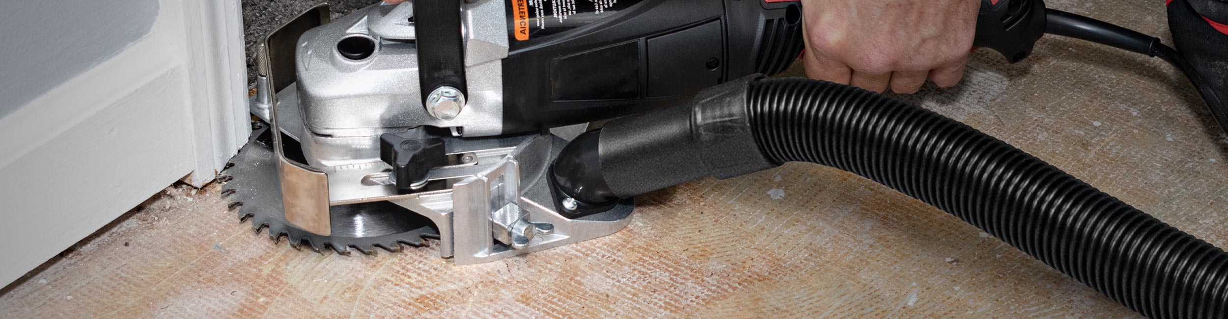 A ROBERTS Longneck Plus 6 inch Jamb Saw in-use undercutting a door jamb with vacuum hose connected to its port