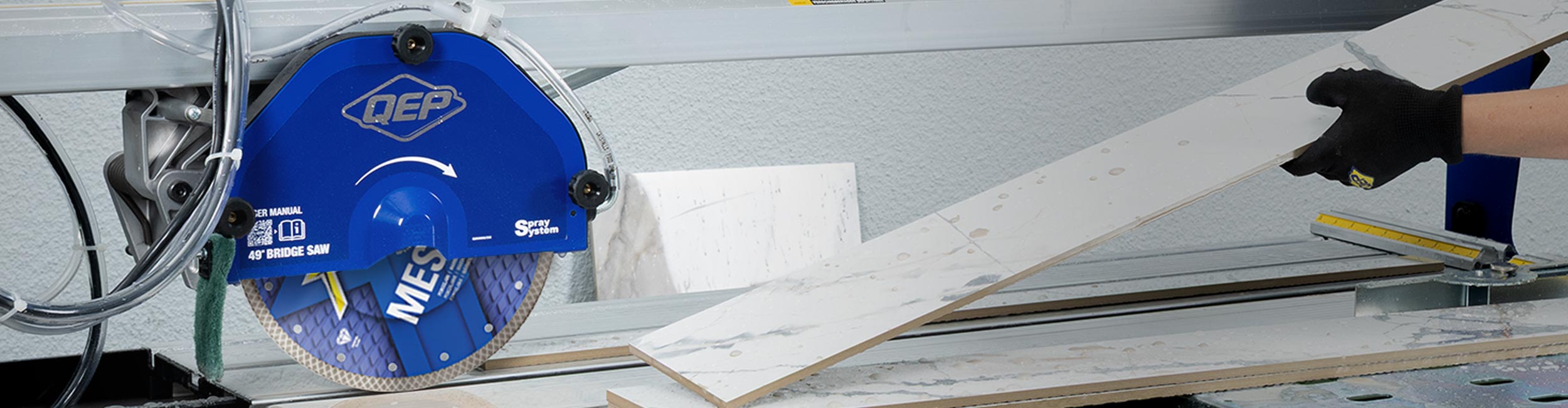 A tile installer cuts a tile with a QEP 700XT - 7 inch Wet Tile Saw
