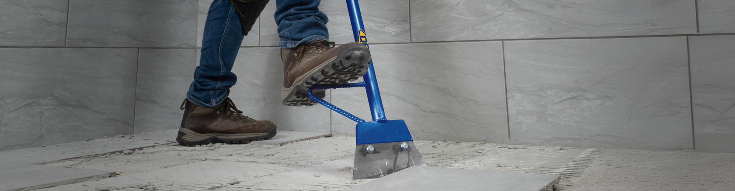 Installer using QEP's 7" Heavy Duty Floor Scraper to remove old tile flooring