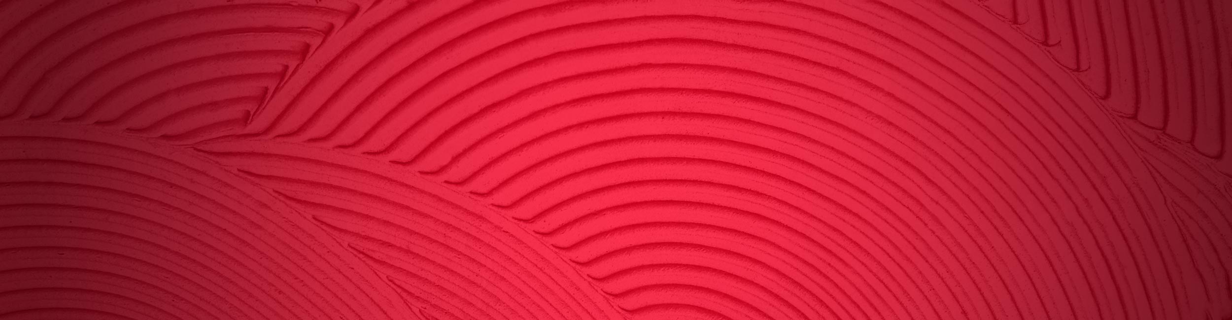 Close-up of textured trowel ridges with circular patterns on a red background