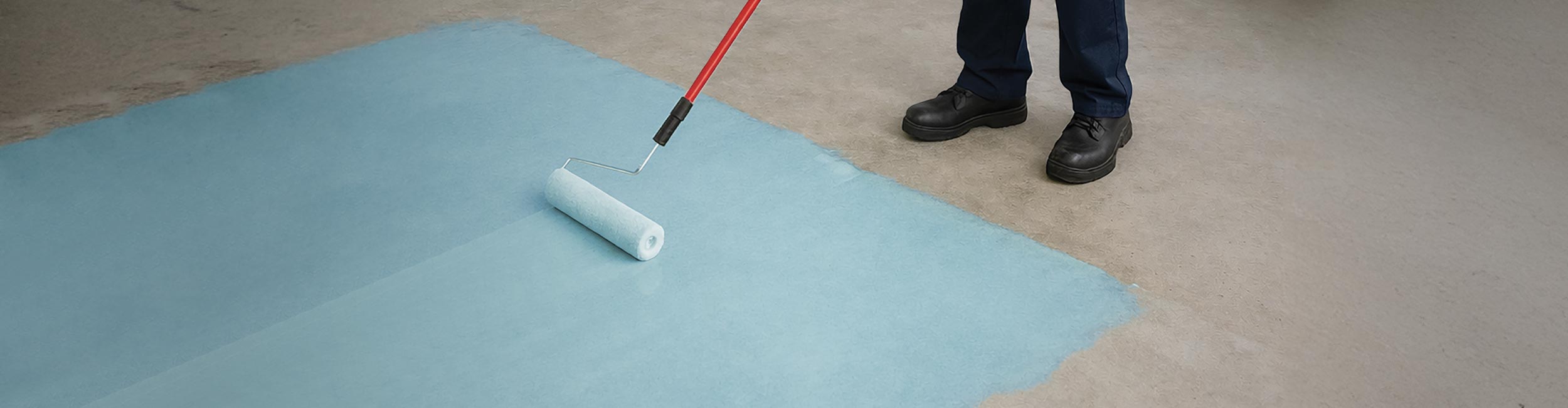 Person priming a concrete subfloor using an extended nap roller with ROBERTS FS400 First Step Primer